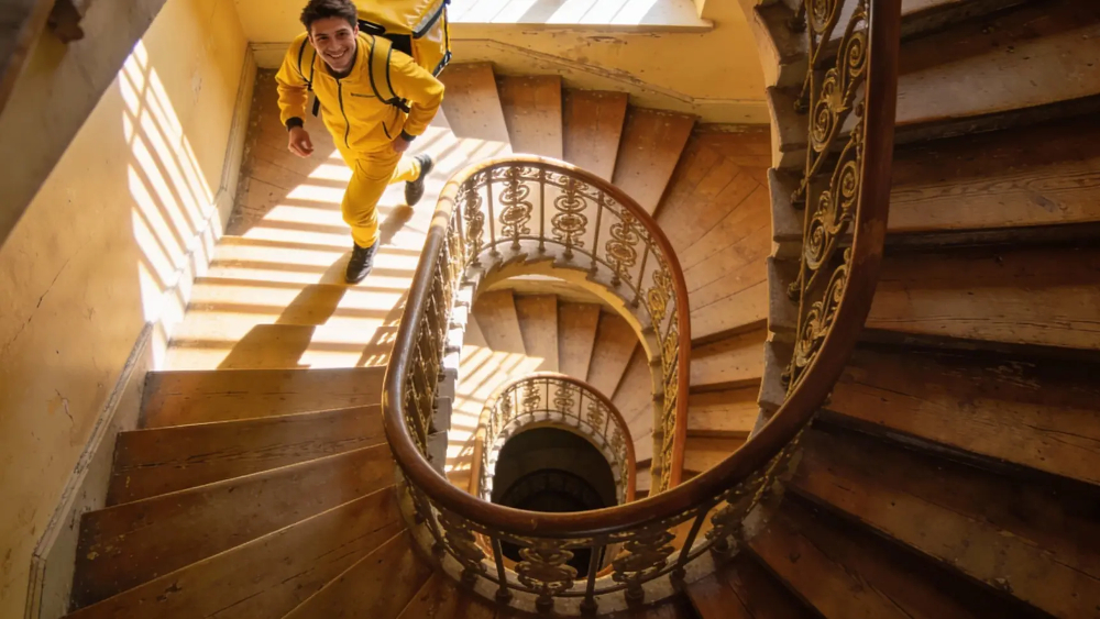 Автокурьер загружает несколько пакетов с едой в багажник машины во дворе